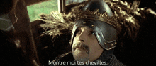 a man with a beard wearing a helmet with the words montre moi tes chevilles below him
