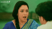 a woman in a blue saree is talking to a man in a white shirt ..