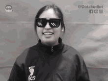 a black and white photo of a woman wearing sunglasses and a shirt that says ics