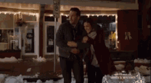 a man and woman are hugging in front of a store that says hallmark movies and mysteries