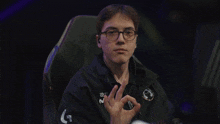 a man wearing glasses and headphones is making a peace sign with his hands