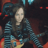 a girl wearing headphones is playing a guitar in front of a dxracer chair