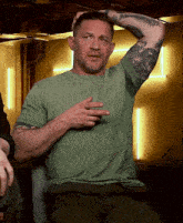a man in a green shirt has a tattoo on his arm that says ' a ' on it