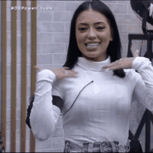 a woman is wearing a white turtleneck and jeans and smiling