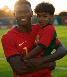 a soccer player is holding a young boy in his arms on a soccer field .