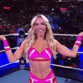 a woman in a pink bikini is standing in a wrestling ring with the word raw behind her