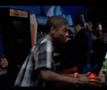 a man in a plaid shirt is standing in front of an arcade machine that says ' king kong ' on it