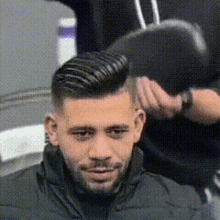 a man with a beard is getting his hair cut by a hairdresser