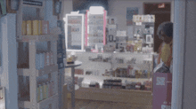a woman wearing glasses and a yellow scarf is standing in front of a display case of condiments