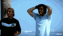 a man in a nike shirt stands next to another man in a baseball cap