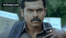a man with a mustache and a ring on his finger is holding a camera .