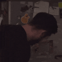 a man in a black shirt is standing in front of a refrigerator with a sticker on it .