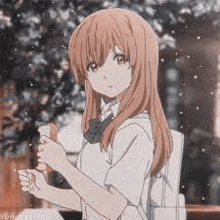 a girl with long hair and a backpack is standing in front of a tree holding a book .