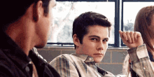 a man in a plaid shirt is sitting next to a woman in a room with other people .