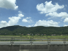 a road with a fence and mountains in the background on a sunny day