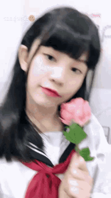 a girl in a sailor uniform is holding a pink rose