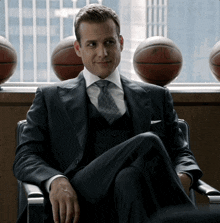 a man in a suit and tie is sitting in front of a window with basketballs on it and one has the number 10 on it
