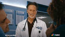 a doctor with a stethoscope around his neck is talking to a group of people in a chicago medical center room