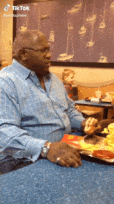 a man is sitting at a table with a plate of food in front of him and a sign that says tiktok on it