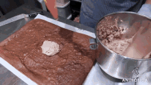 a person is making a brownie with a bowl of frosting next to it