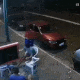 a red car is parked on the side of the road in front of a building .