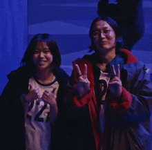 a girl wearing a number 22 jersey stands next to a man in a red jacket