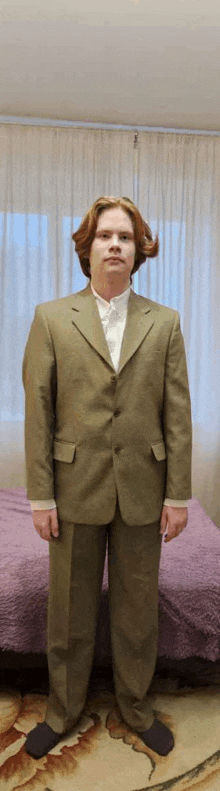 a man in a suit stands in front of a purple bed