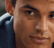a close up of a man 's face with a blue shirt