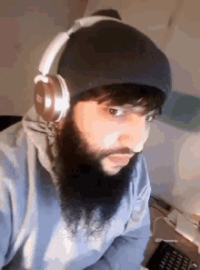 a man with a beard wears headphones and a beanie