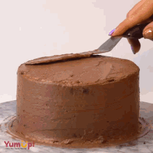 a person is frosting a chocolate cake with a spatula and the words yum up behind them