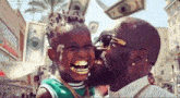 a man is kissing a little boy on the cheek .