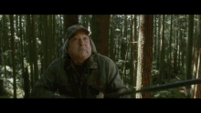 a woman with red hair is standing in the woods looking at the camera