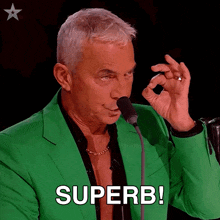 a man in a green suit holds a microphone and says superb