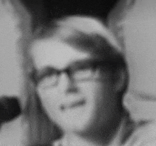 a black and white photo of a man wearing glasses and a headband .