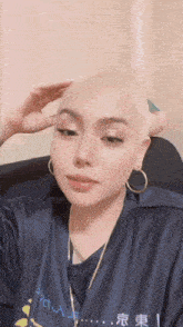 a woman with a shaved head is wearing a shirt that says a