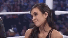 a woman is sitting in a boxing ring smiling .