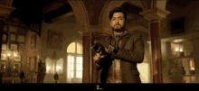 a man holding a gun in a room with the number 2 on the bottom right