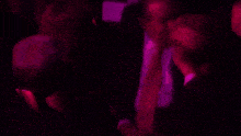 a man and a woman are sitting in a dark room with purple lights behind them .