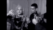 a black and white photo of a woman holding a glass of wine .