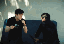 a man in a black shirt with a picture of a car on it stands next to another man