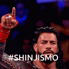 a wrestler with a tattoo on his arm holds up his finger and says # shinjismo