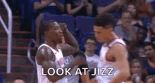 a basketball player is flexing his muscles while standing next to another player .