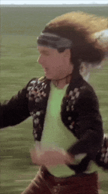 a man wearing a headband and a green shirt is running