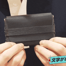 a person is holding a black wallet with a blue sticker that says ' a ' on it