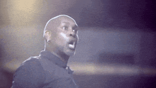 a bald man in a black shirt is making a surprised face