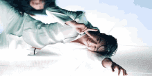 a man is laying on his stomach on the floor making a peace sign with his hands .
