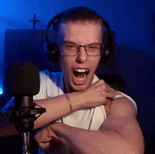 a man wearing headphones and a bracelet stands in front of a microphone
