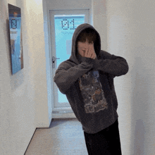 a man in a hoodie covering his face in front of a door that says training