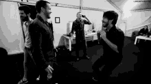 a group of men are standing in a room and one of them is holding a microphone