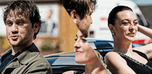 a man and a woman are sitting in a car with a white van in the background